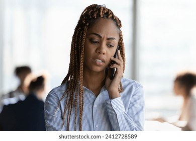 Serious young ethnic female manager employee take break in office teamwork to stay alone make answer important phone call. Focused biracial woman expert help client to solve business problem remotely - Powered by Shutterstock