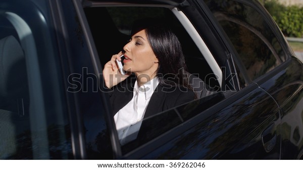 Serious young\
executive on phone in\
limousine