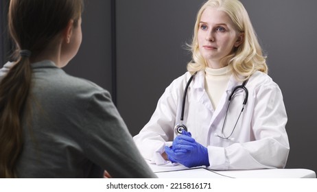 Serious Young Female Doctor Talking To A Female Patient. Checks Medical History Rear View Young Woman Listening To Doctor At Checkup Meeting.