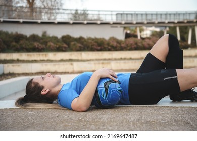 Serious young female football player lying on ground in park - Powered by Shutterstock