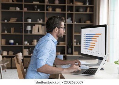 Serious young freelancer man analyzing business diagram, marketing statistics on desktop monitor. Broker, investor studying project data charts, rates, using job application for strategy analysis - Powered by Shutterstock