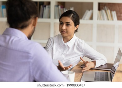 Serious young indian ethnicity business lady discussing online project with african colleague at briefing meeting. Concentrated two mixed race managers employees working on computer in office.