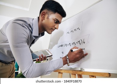 Serious Young Indian Software Engineer Drawing Block Diagram On Whiteboard