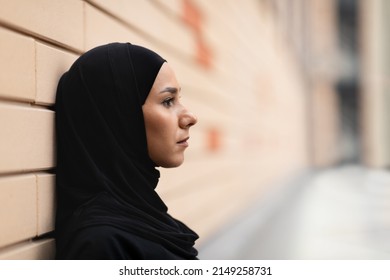 Serious young islamic female athlete in hijab leans on brick wall, think and rests after jogging. Urban workout, sports in city, health care and sports during covid-19 pandemic, close up, profile - Powered by Shutterstock