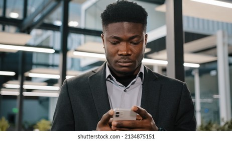 Serious Young Man African American Office Worker Searching Smartphone Internet Choosing Making Order Chatting Online With Friends Scrolling Mobile Phone Thoughtful Male User Click At Browser Account