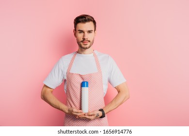 Serious Young Man In Apron Holding Air Freshener On Pink Background