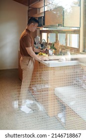 Serious Young Man Cooking Breakfast At Kitchen Counter