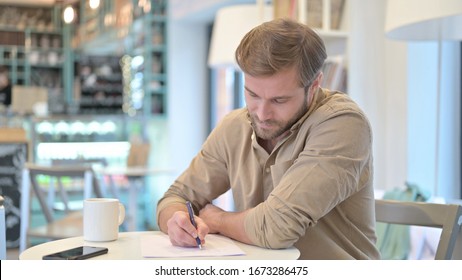 Seriöser junger Mann, der Paperwork im Café macht