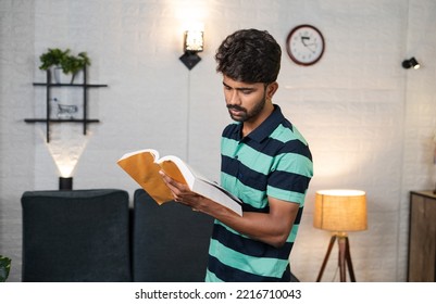 Serious Young Man Reading Book By Walking Around For Examination Preparation At Home - Concept Of Knowledge, Learning And Dedication.