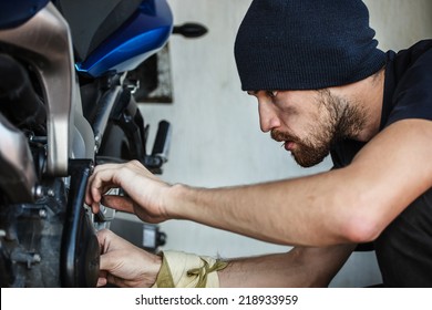 Serious Young Man Repairing His Motorcycle.