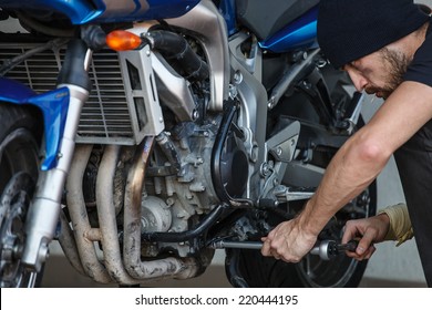 Serious Young Man Repairing His Motorcycle 