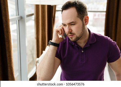 Serious Young Man Talking On The Phone At Home Or In The Office