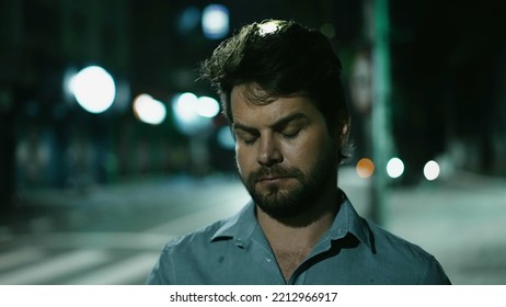 Serious Young Man Walking At Night In Downtown City Street. Thoughtful Pensive Person Walks Forward At Night In Urban Sidewalk