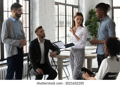 Serious Young Multiethnic Colleagues Coworkers Gather At Casual Meeting In Office Engaged In Team Thinking Brainstorming. Diverse Multiracial Businesspeople Talk Discuss Business Ideas Together.