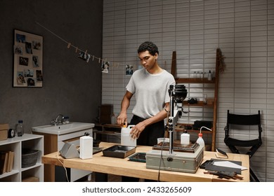 Serious young photographer engaged in analog film development in a professional darkroom setting - Powered by Shutterstock