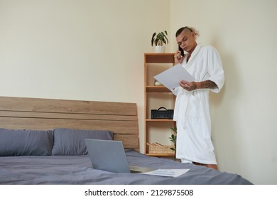 Serious Young Project Manager In Bathrobe Making Phone Call To Discuss Report With Colleague In The Morning