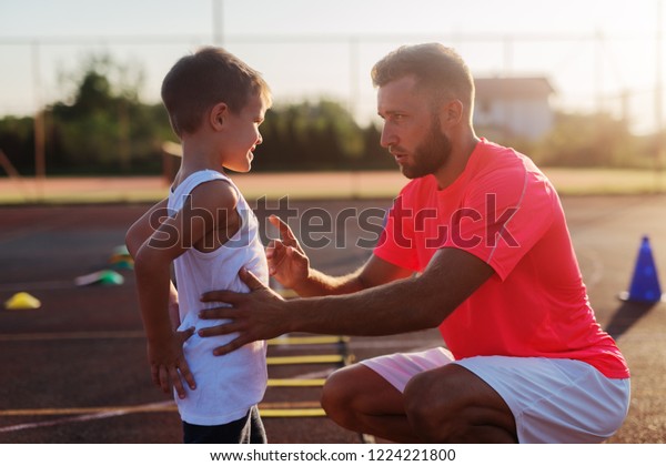 Serious young trainer giving lecture\
to a little boy because of his bad acting on\
training.