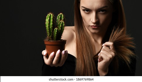 Serious young woman in bad mood shows with long silky straight hair holds cactus plant in pot and comparing with hair split ends over background with copy space. Haircare, beauty, wellness concept