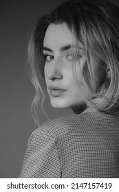 Serious Young Woman In Grey Suit Looking Back Over Shoulder Closeup View, Monochrome