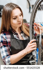 Serious young woman pumping the wheel of the bicycle - Shutterstock ID 551425528