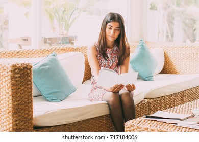 Serious Young Woman Reading Booklet In Hotel Lobby