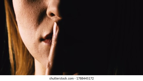 Seriöse Frau, die den Finger auf die Lippen legt - schweigen oder geheim halten. Mund, Nahaufnahme