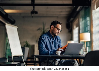 Serious-looking man working at the office, reading his notebook. - Shutterstock ID 2213425651