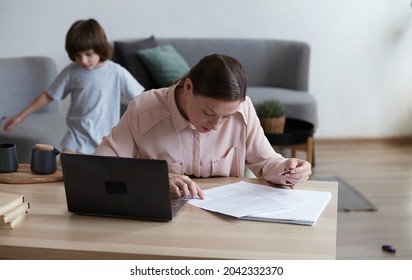 Seriously Frustrated Young Mom And Son Pay Using Credit Card And Laptop Private Daycare Kindergarten And School Bills. Buying Baby Products Online, Paying For Education And Rent