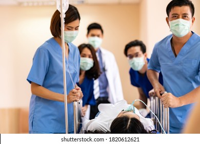 Seriously Injured Patient With Oxygen Mask On Gurney Stretcher Bed Pushed By Medical Team Of Doctor Nurse And Paramedic To The Operating Room. Emergency Health Care And Medical Hospital Concept.