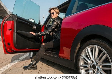 Seriously Successful Young Woman Open The Door Of Her Car. Get Out Of The Car.Beauty In Style. Attractive Young Stylish Woman In Eyeglasses Getting Out Of Her Car