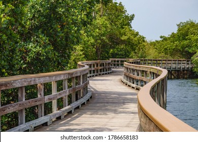 Serpentine boardwalk, part of a long nature trail, across a tidal marsh in a nature preserve in west central Florida, USA (foreground focus), for themes of conservation, environment, and recreation