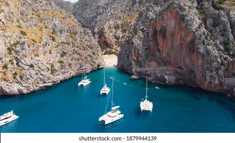 Serra De Tramuntana,Sa Calobra, Torrent De Pareis Beach, Aerial ,crystal Clear Water Of Mediterranean Sea With Moored Sailing Boats And Yacht Going Towards The Beach. High Quality Photo