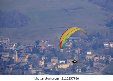 Serramazzoni, Italy - January 2022:Paraglider Flies In The Air. Aerial View Of Paragliding. Paraglider Flies Above The Small Town In A Bright Sunny Day. Concept Of Extreme Sport.
