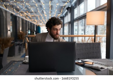 serrious guy cannot solve some problems, watching passers-by who is walking on the street. close upphoto. guy sitting behind the laptop