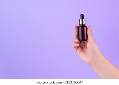 Serum bottle in female hands, top view. Transparent moisturizer for skin care. Nourishing essential oil in glass bottle with pipette. Liquid emulsion with hyaluronic acid. Beauty cosmetic spa product