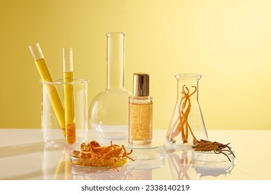 A serum bottle unbranded displayed on yellow background with some lab equipment containing cordyceps and essence. Space for design packaging. Front view, concept for rare chinese herbs