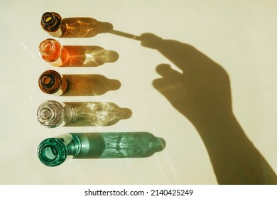 Serum with collagen and peptides in colorful glass bottles on beige background with sunlight shadow. Skincare essence for beautiful healthy skin. Top view.