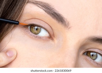Serum for growth and density of eyelashes with oils and peptides. Close-up of a girl's eyes with a serum brush. The eyes of a young woman in close-up. The concept of preventing hair loss.