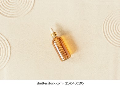 Serum Or Liquid Collagen Dropper Bottle On Sand Background. Anti Age Cosmetics Products. Skin Care Beauty Products, Summer Concept. Japanese Zen Garden With Rounds On Sand. Above View, Beige Color