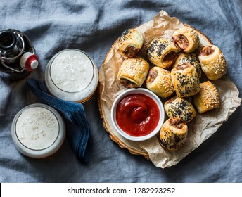 Served appetizers table - minced puff pastry rolls and beer on grey background, top view. Flat lay. Sausage rolls       