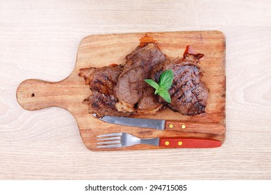 served beef meat barbecue on wooden plate with cutlery