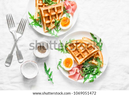 Served breakfast with potatoes savory waffles, boiled egg, ham and arugula on light background, top view. Appetizers, snack, brunch. Delicious healthy food concept. Flat lay  