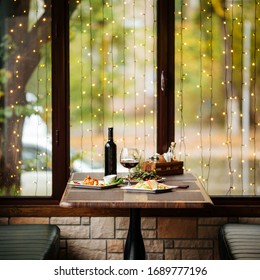 Served Celebration Dinner With Red Wine And Salad, Wooden Table, Lights, Square, Side View