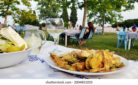 Served Delicious Greek Traditional Food In A Restaurant Taverna Outside. Summer Vacation In Chalkidiki, Greece. Fried Zucchini, White Wine, Greek Salad.