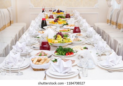 Served holiday table, cutlery, crockery, snacks, glasses, white tablecloth, chairs