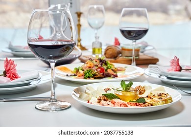 A served restaurant table with glasses of red wine and appetizer awaits guests. Close-up, selective focus - Powered by Shutterstock