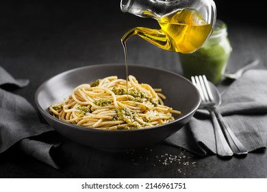 Served spaghetti with fresh basil pesto and pouring with olive oil bottle closeup - Powered by Shutterstock