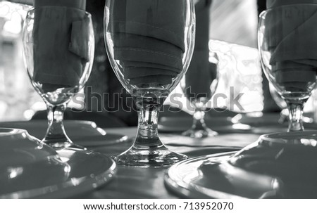 Served table with glasses. Clean diningware on table black and white photo. Empty wine glass and plate vintage banner. Hospitality of restaurant or cafe. Restaurant table. Celebration guest waiting