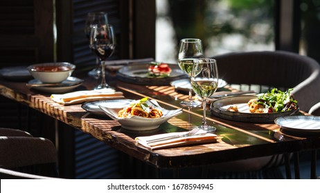 Served Table With Italian Food - Seafood Pasta, Salad And Wine With Window Light