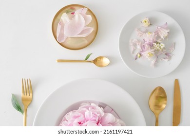 Served Table With Plates And Golden Cutlery On A Light Background, Flowers Replace Food. Edible Live Fresh Flowers
